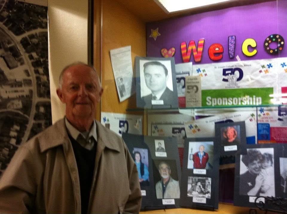 Neil MacNeil beside the 50th anniversary display of past staff, outside the library